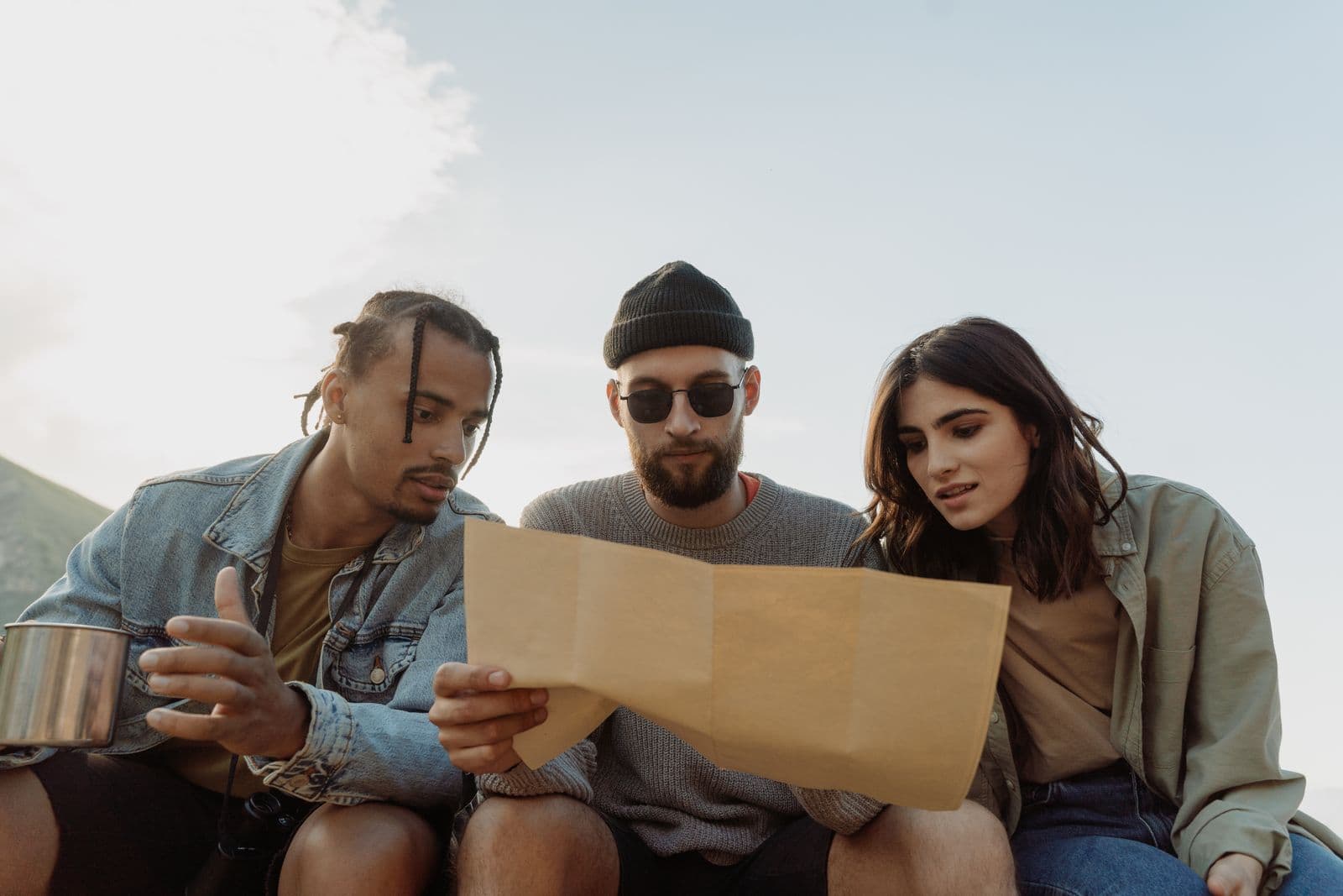 Three friends studying a paper map together while planning a trip
