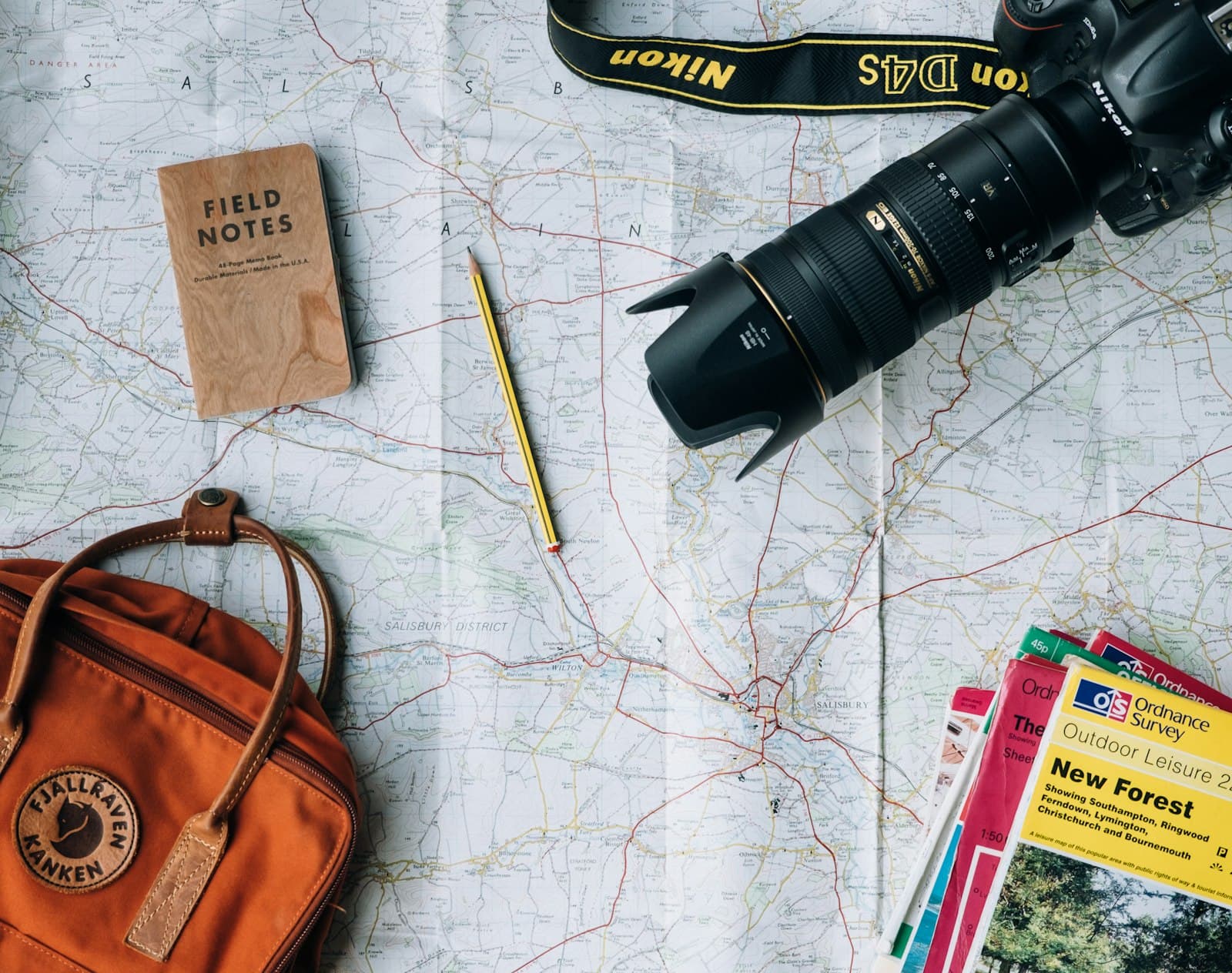Travel map, notebook, camera and backpack laid out for planning a group trip